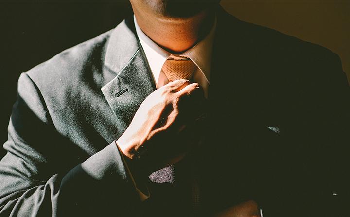 Photo of man in suit straightening tie